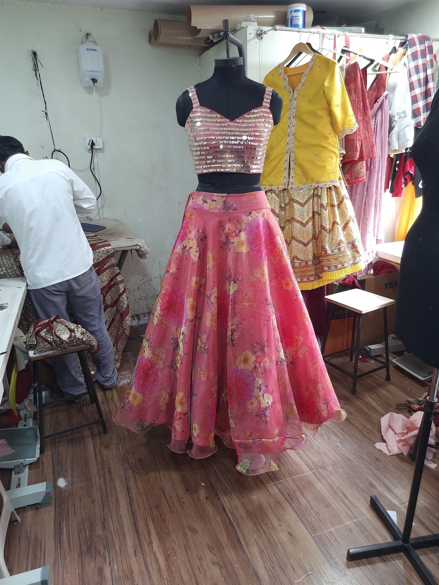 A tailor at work at Fusion Tailoring, garments in progress on the rack behind him